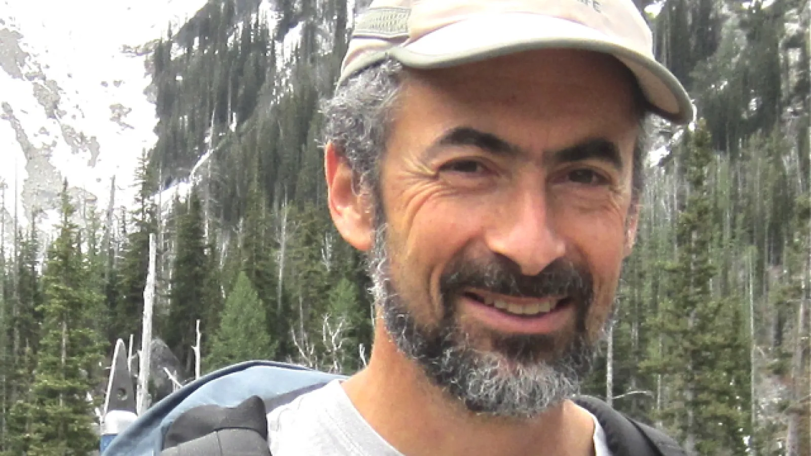 David Kaplan smiling with dense woods and large mountain behind him