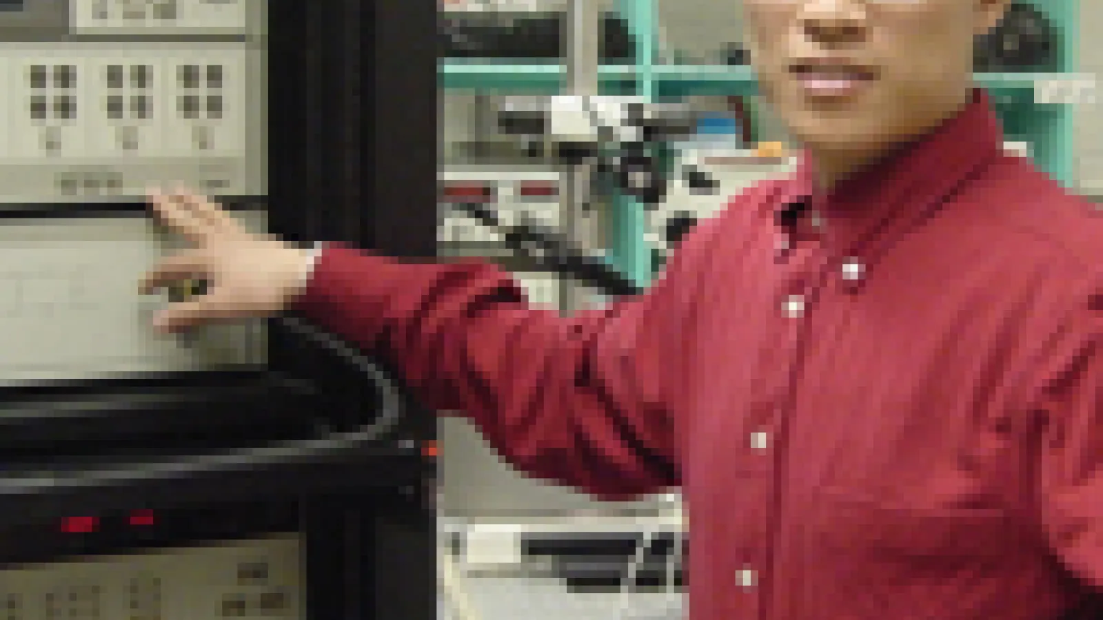 Mingzhong Wu standing in lab pointing at harddrive