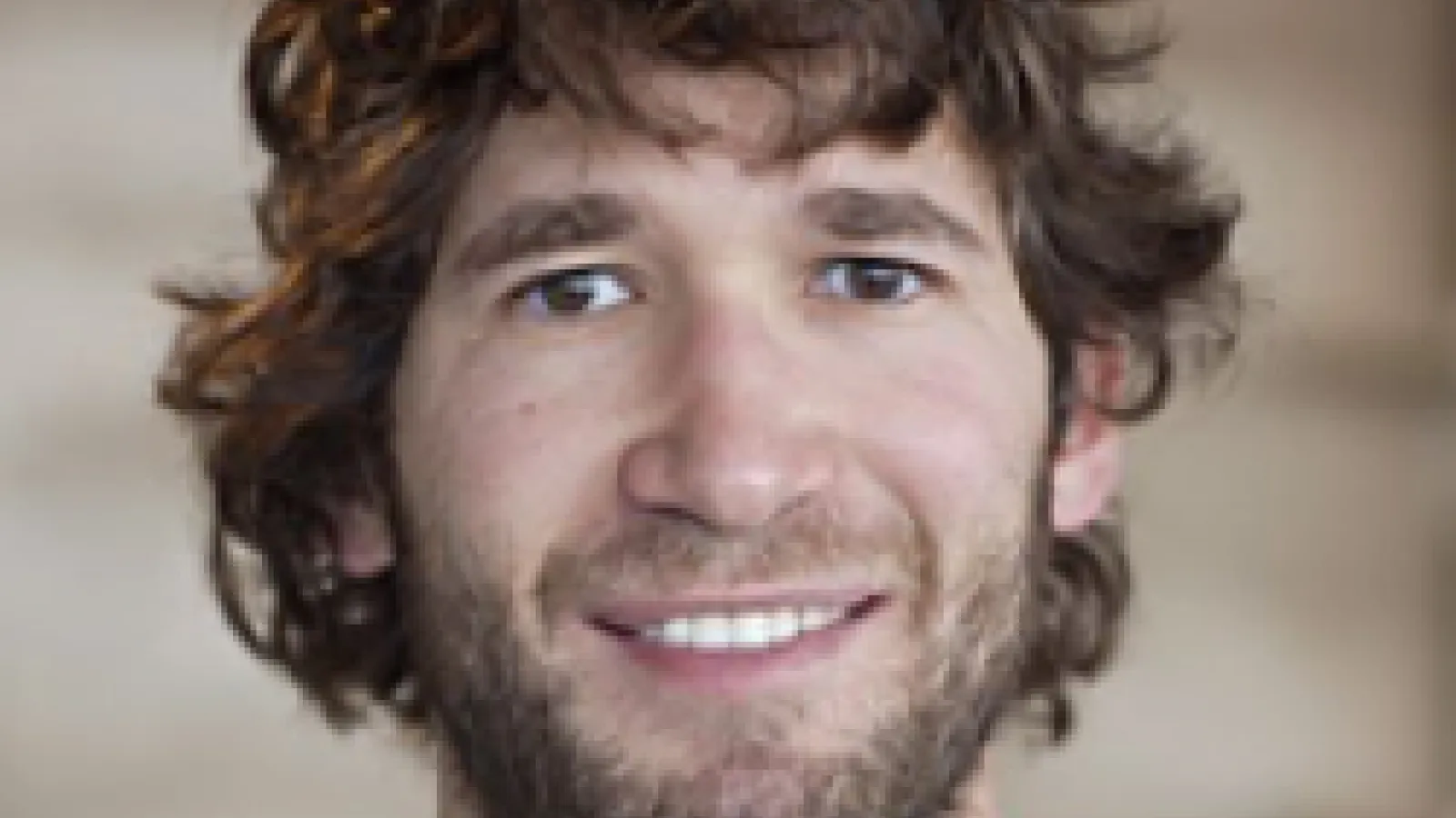 Daniel Holz smiling with brown background