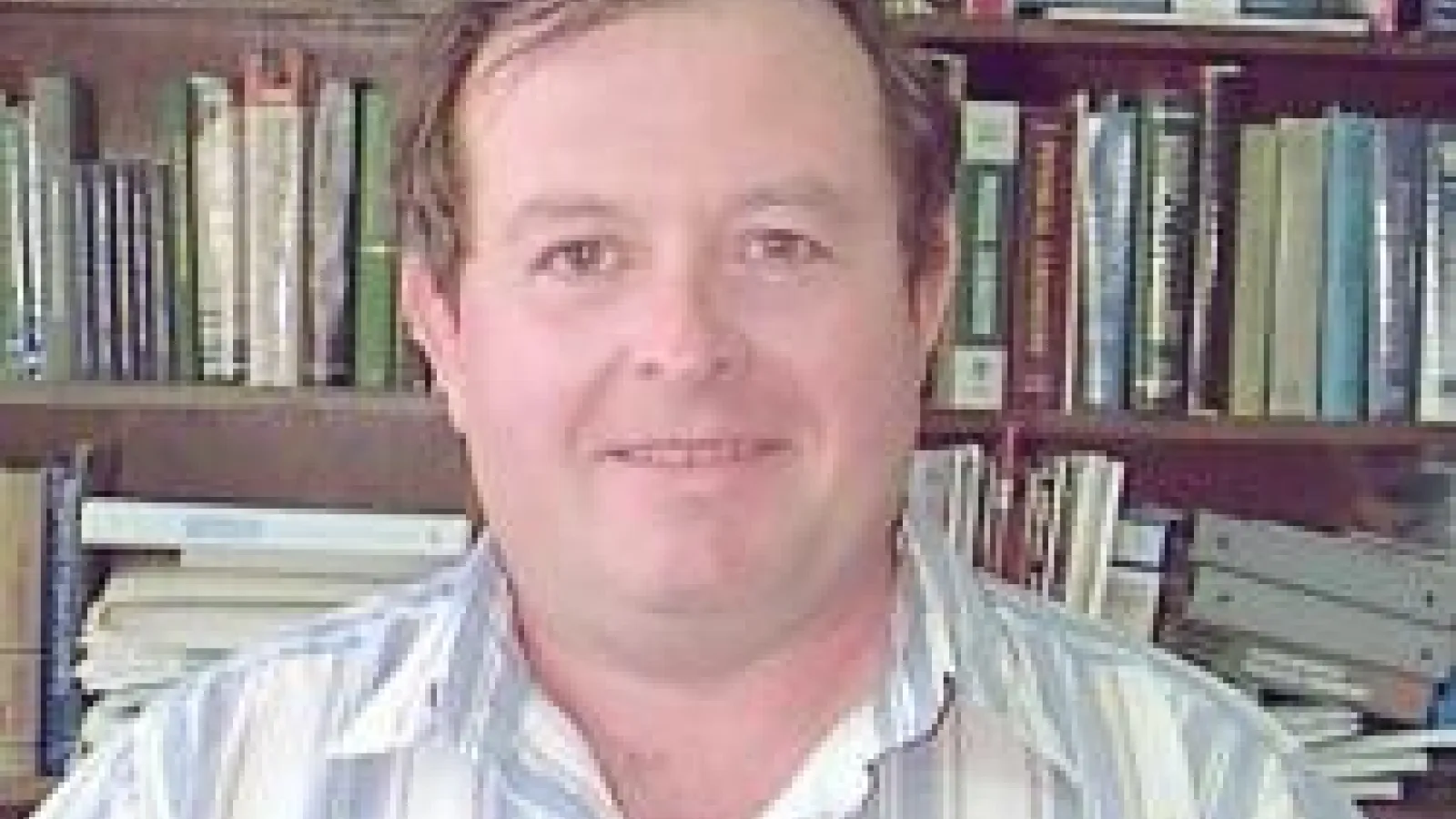 Mark I. Stockman smiling with bookshelf behind him