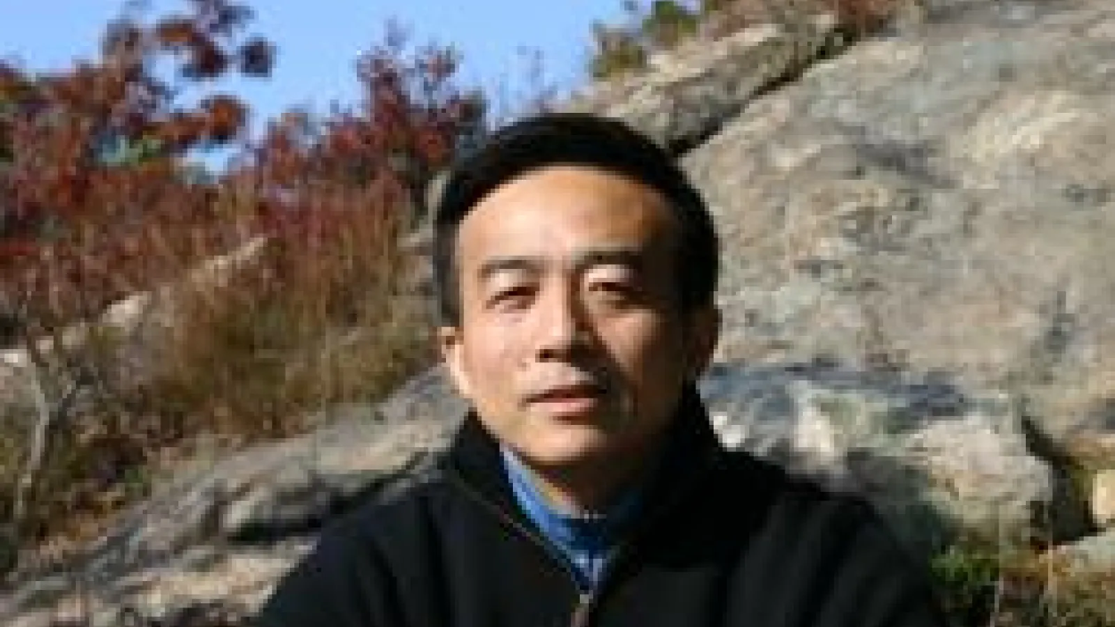 Yuhai Tu with rocky slope behind him