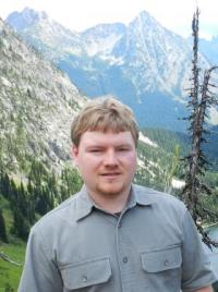 Student on mountain with ridgeline and trees in background
