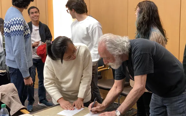A student talking and getting an autograph from Pierre Agostini