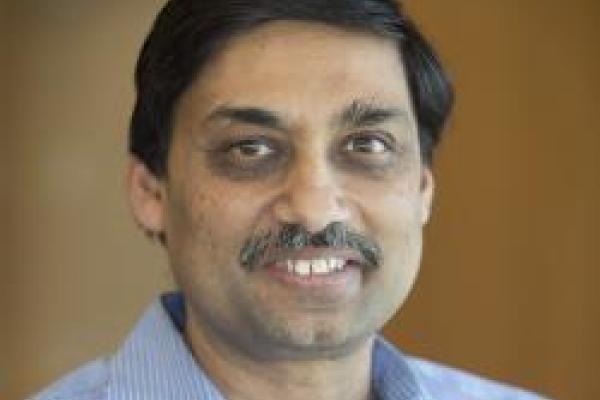 Samir Mathur smiling with brown background