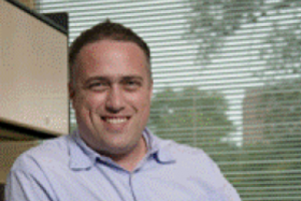 Ezekiel Johnston-Halperin smiling in his office with window behind him
