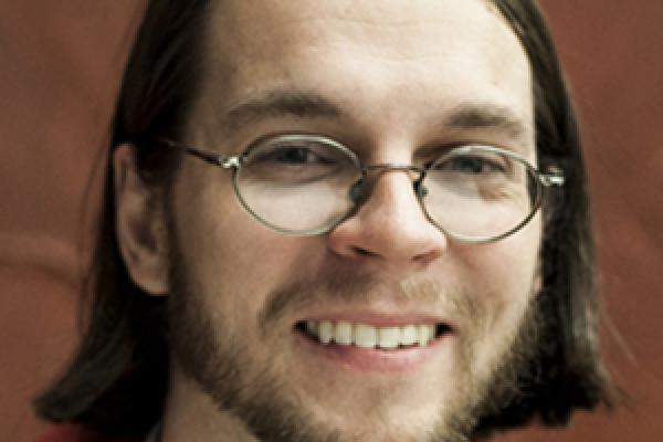 Chris Orban smiling with brown background