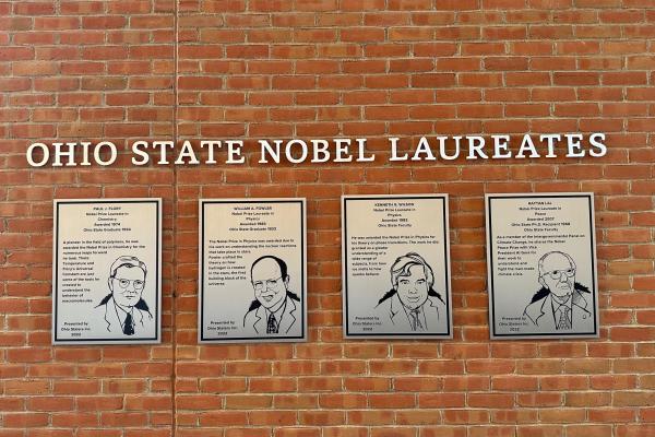 Photo of brick wall with silver plaques of four Ohio State Nobel Laureates