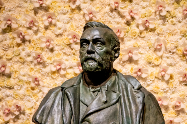 Statue of Alfred Nobel with flowers behind him