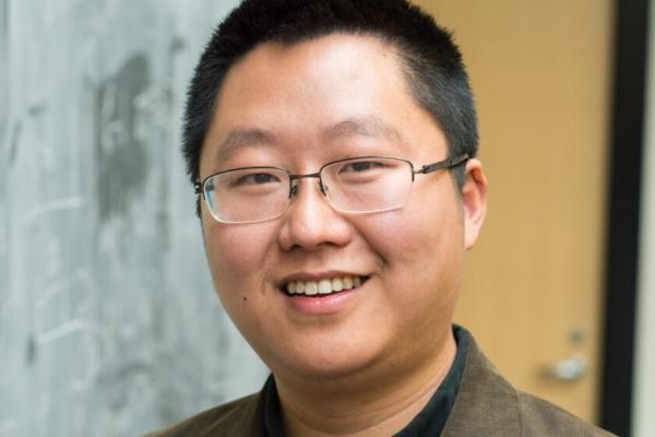 Liang Fu smiling in front of a door