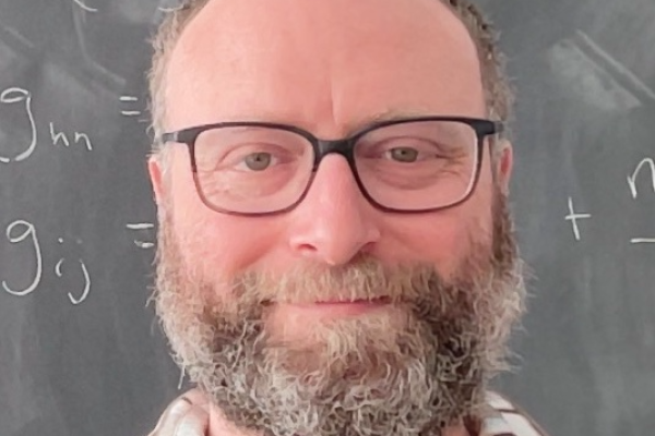 Tim Cohen in front of a chalkboard