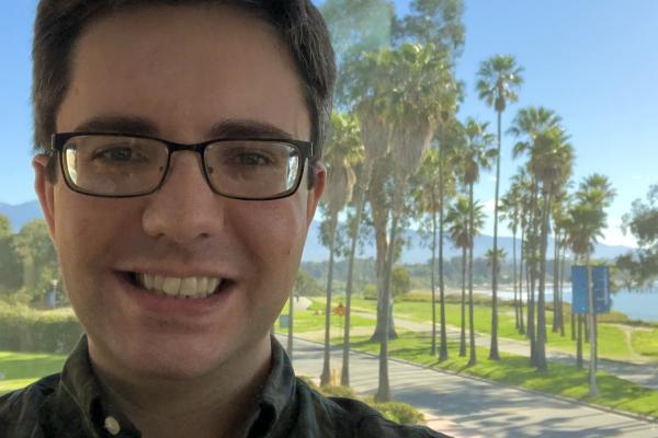 Grant Remmen smiling in front of a grove of palm trees