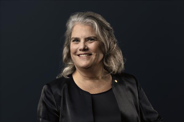 Andrea Ghez against plain black background with one hand on hip