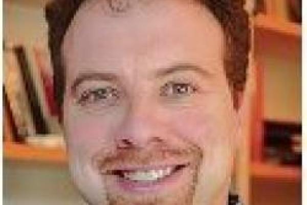 A close-up of Adam Riess with a bookshelf in the background.