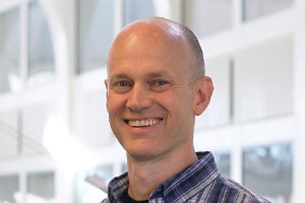 John Beacom smiling and standing in PRB Atrium