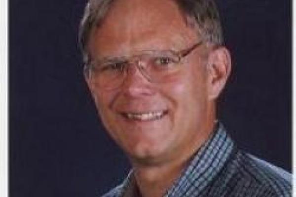 Eric Braaten smiling with navy blue background