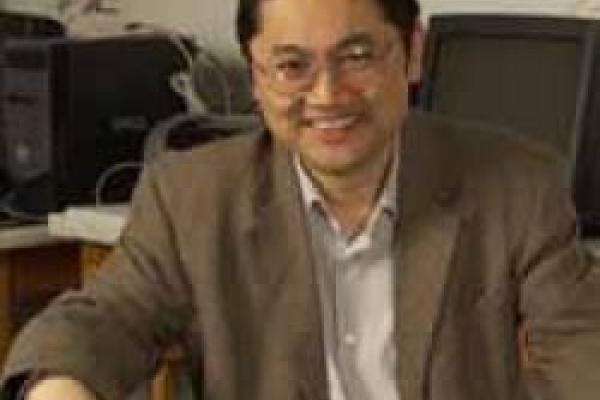 Dongping sitting on chair and smiling with computers in the background