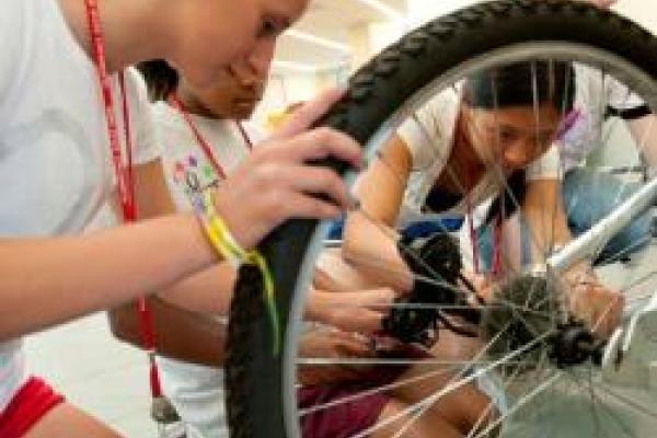 Students working on fixing a bicycle tire gear