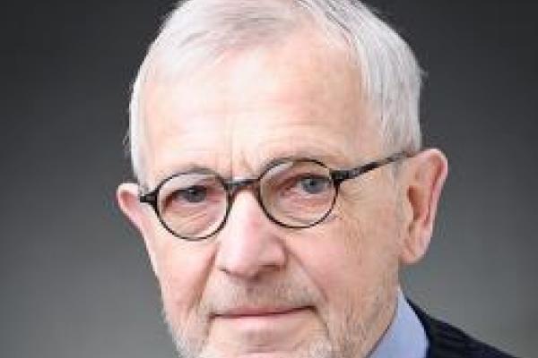 A headshot of Francis Halzen with a grey background.