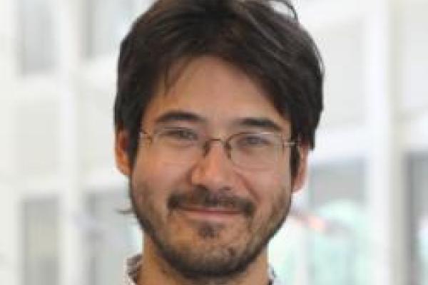 Chris Hirata smiling with blurred out PRB atrium in the background
