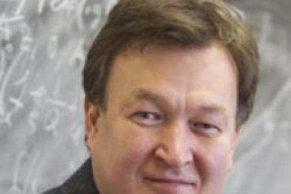 Dmitri Kharzeev with chalkboard behind him