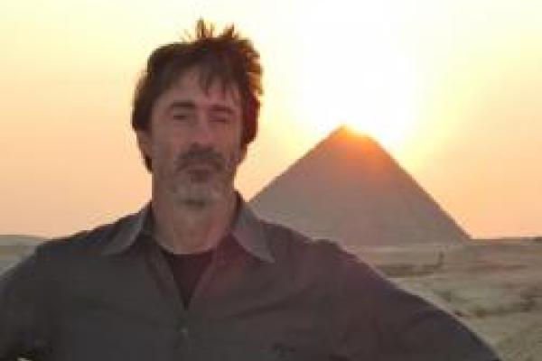 Mike with hands on hips standing in the desert in front of the great pyramids