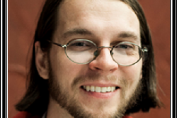 Chris Orban smiling with brown background and black frame border
