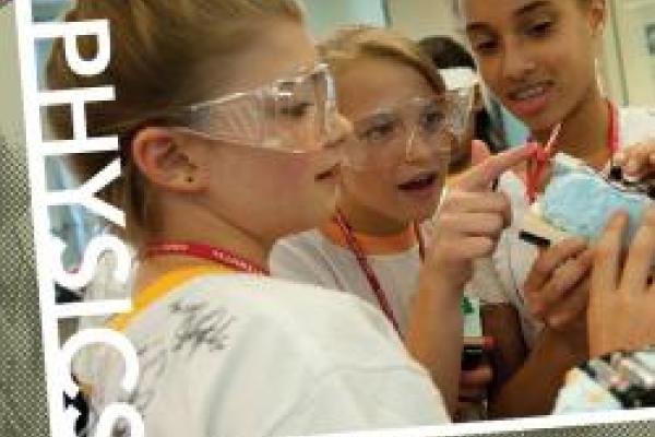 Students in protective goggles talking and working on an experiment