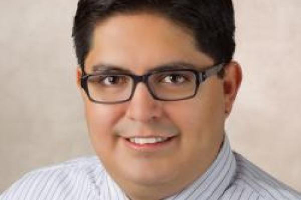 A headshot of Rolando Valdes Aguilar with a cream background.