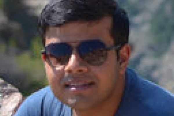 D Chowdhury in sunglasses sitting on a rock