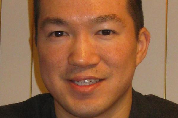Eric Feng smiling in front of striped wall