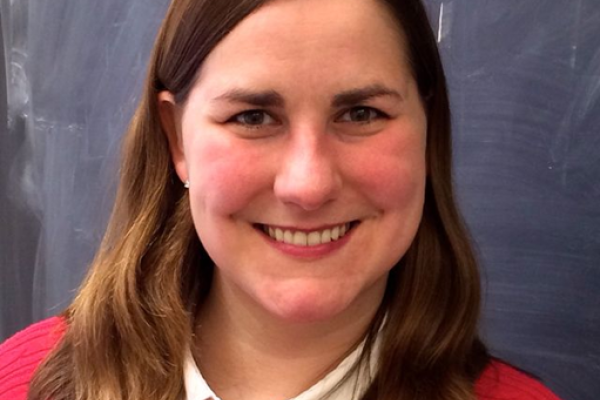 Adrienne Erickcek smiling with empty blackboard behind her