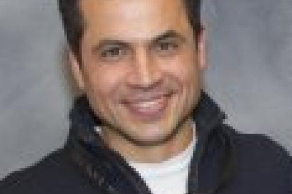 Cristian Batista smiling with grey background
