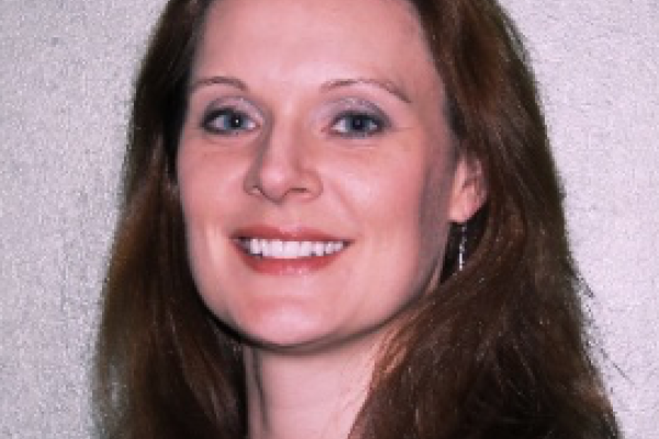 Kelly Denney smiling with light grey background