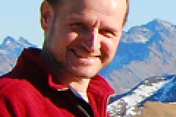 Maciej Maska smiling with mountain range behind him