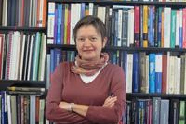 Vesna Mitrovic with arms crossed in front of bookshelves