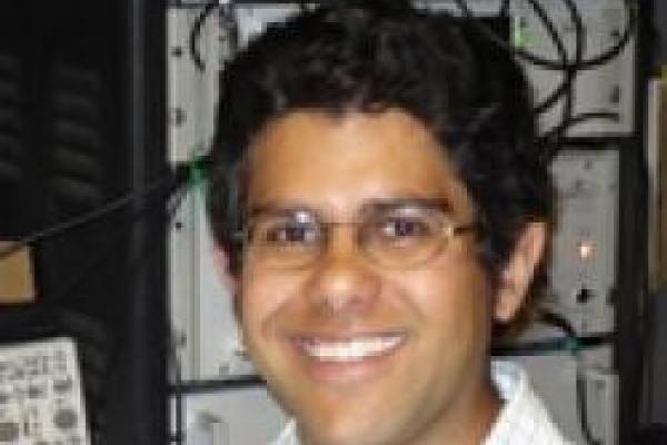 Jay Gupta smiling and standing in front of computer hard drive