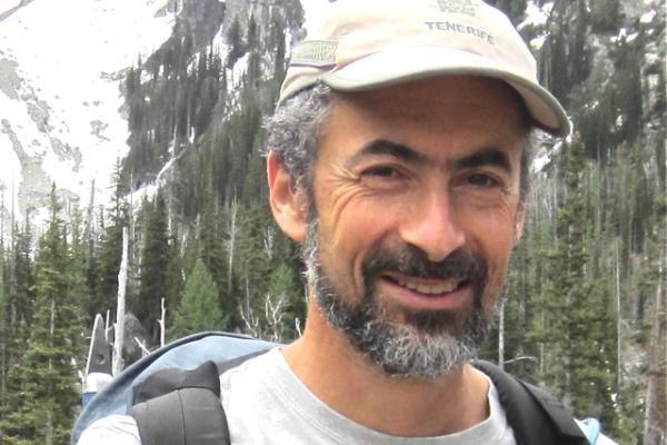 David Kaplan smiling with dense woods and large mountain behind him