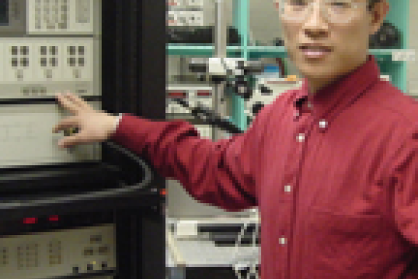 Mingzhong Wu standing in lab pointing at harddrive