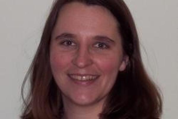 Wendy Panero, a white woman with shoulder length brown hair, smiles into the camera against a white background. She is wearing a burgundy blouse and minimal makeup.