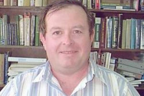 Mark I. Stockman smiling with bookshelf behind him