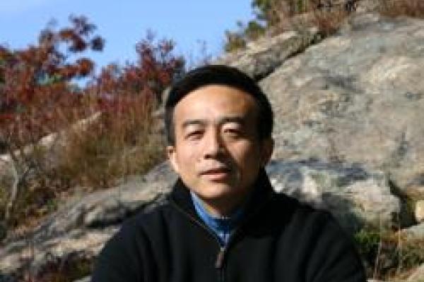 Yuhai Tu with rocky slope behind him