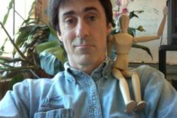 An image of Professor Mike Lisa with a wooden figurine on their shoulder.