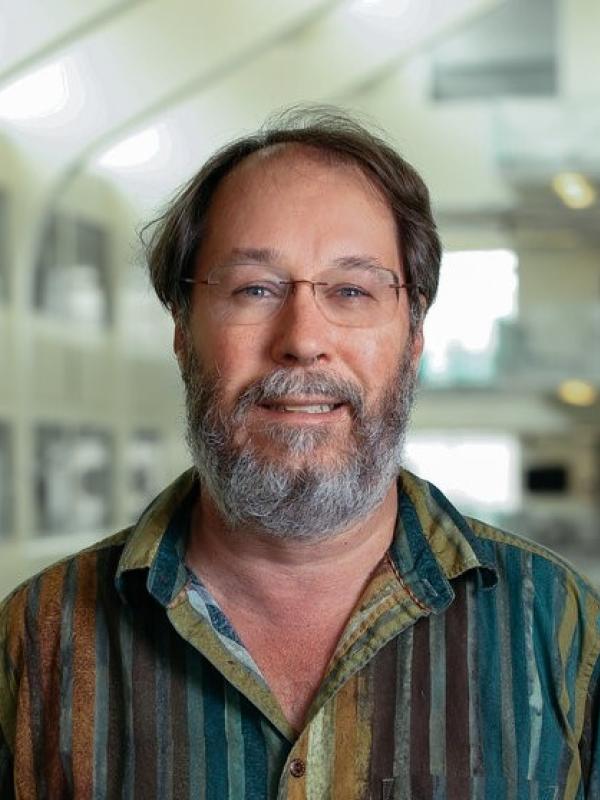 Headshot of James Beatty smiling with blurry PRB Atrium in the background