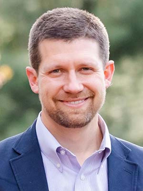 Robert Baker smiling with blurred trees behind him