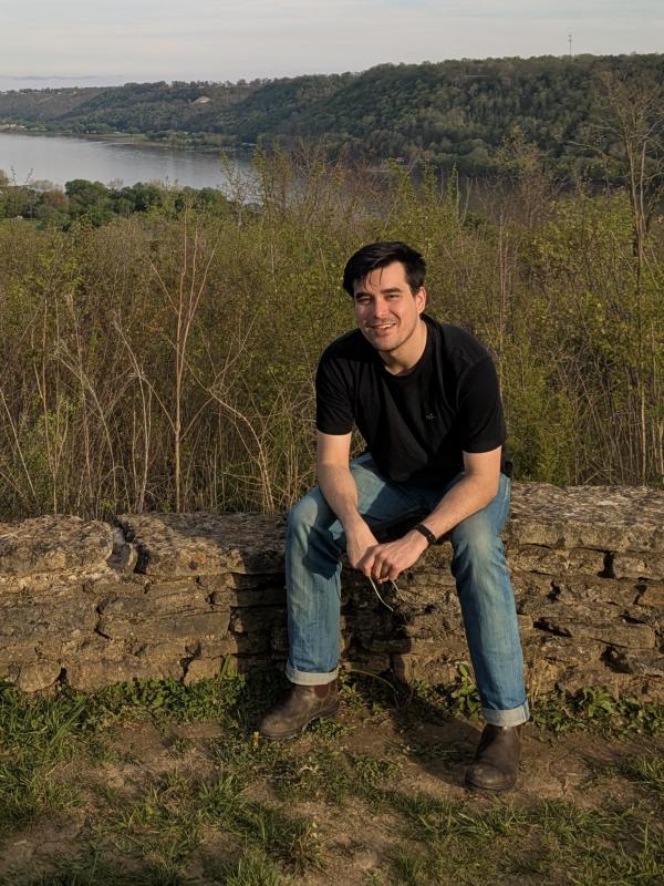 Daniel sitting on an old stone wall, overlooking the Ohio River.