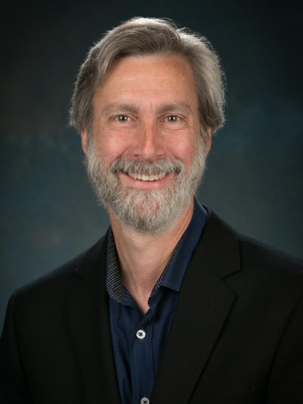 Close up of David smiling with a dark grey background
